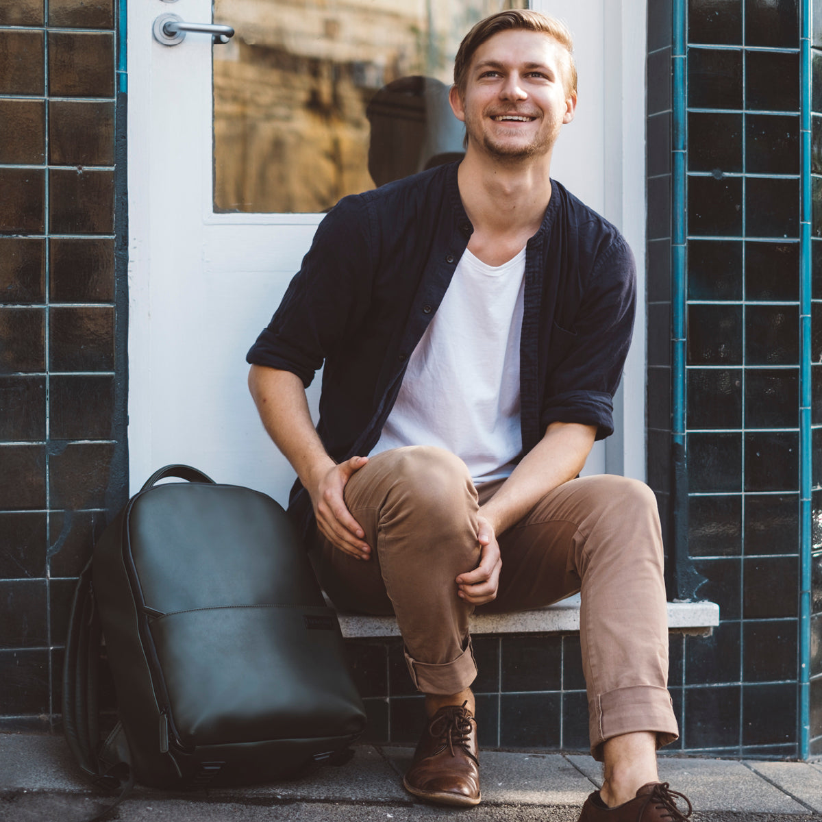Male sitting down with No More Ugly Camera Backpack